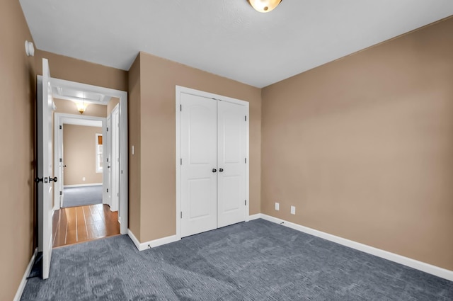 unfurnished bedroom featuring a closet and dark colored carpet