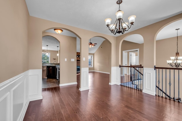 unfurnished room with plenty of natural light, dark wood-type flooring, ceiling fan with notable chandelier, and sink