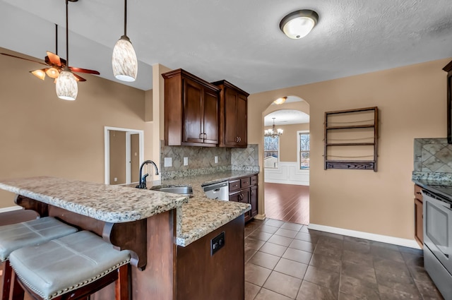 kitchen with sink, backsplash, a kitchen breakfast bar, and kitchen peninsula