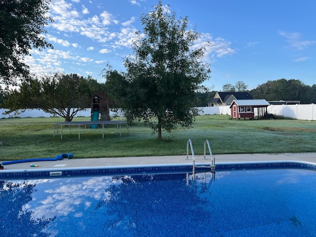 view of pool featuring a yard, a trampoline, and a shed