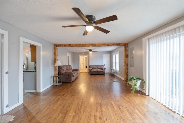 unfurnished living room featuring electric panel, light hardwood / wood-style flooring, and a textured ceiling