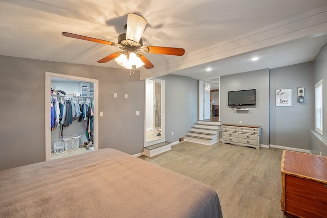 bedroom featuring ceiling fan, a walk in closet, and light hardwood / wood-style flooring