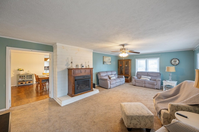 carpeted living room with ornamental molding, ceiling fan, and a textured ceiling