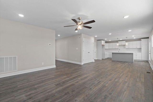 unfurnished living room featuring baseboards, visible vents, a ceiling fan, dark wood-style flooring, and recessed lighting