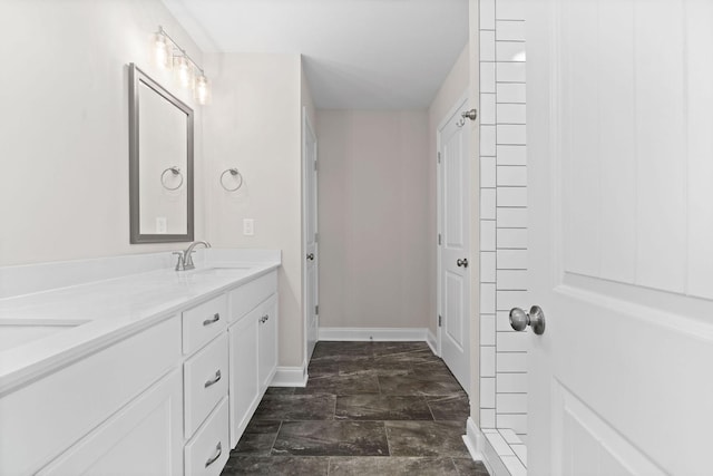 full bathroom with double vanity, baseboards, and a sink