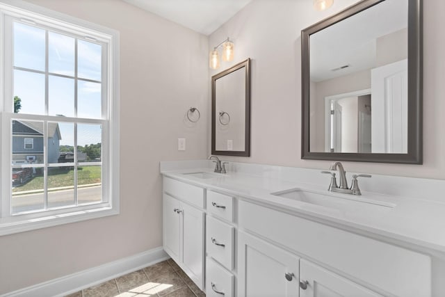 full bathroom with tile patterned flooring, a sink, baseboards, and double vanity