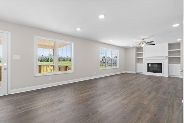 unfurnished living room with dark hardwood / wood-style flooring, ceiling fan, a fireplace, and built in shelves