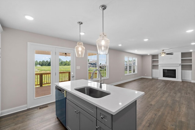 kitchen featuring pendant lighting, sink, gray cabinets, a center island with sink, and stainless steel dishwasher