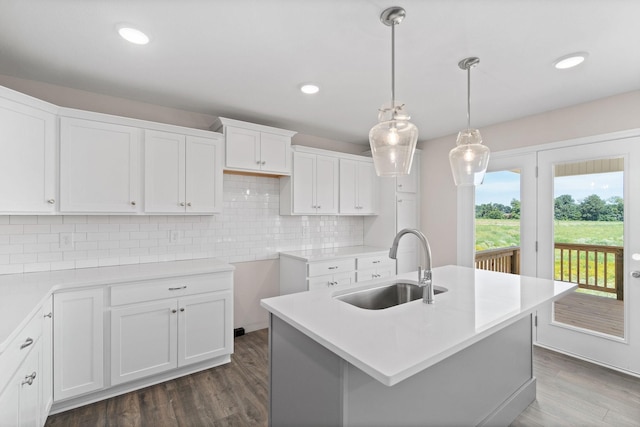 kitchen featuring sink, a kitchen island with sink, white cabinets, dark hardwood / wood-style flooring, and decorative light fixtures