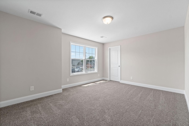 empty room with carpet flooring, visible vents, and baseboards