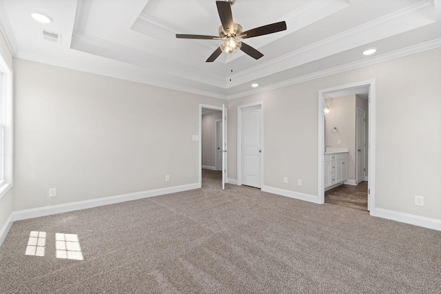 unfurnished bedroom featuring baseboards, visible vents, a raised ceiling, crown molding, and carpet floors