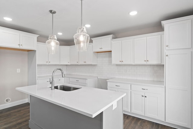 kitchen with sink, white cabinetry, an island with sink, dark hardwood / wood-style flooring, and decorative light fixtures