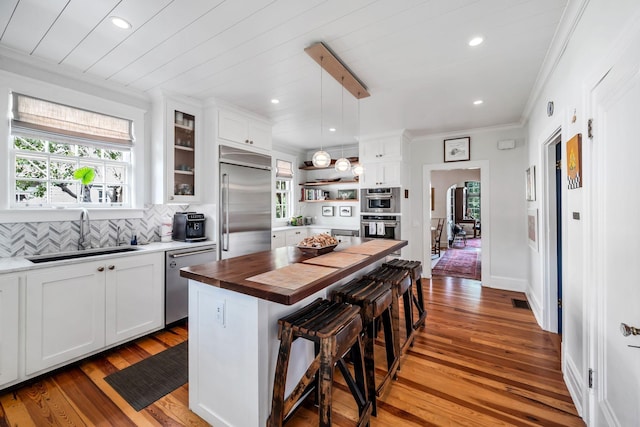 kitchen featuring a breakfast bar, sink, a center island, stainless steel appliances, and white cabinets