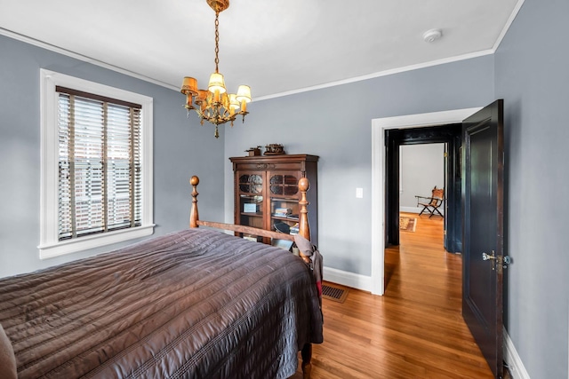 bedroom with an inviting chandelier, crown molding, and hardwood / wood-style flooring