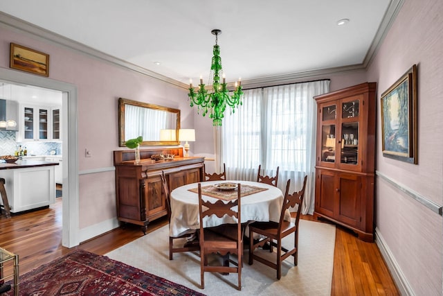 dining area with crown molding, wood-type flooring, and an inviting chandelier