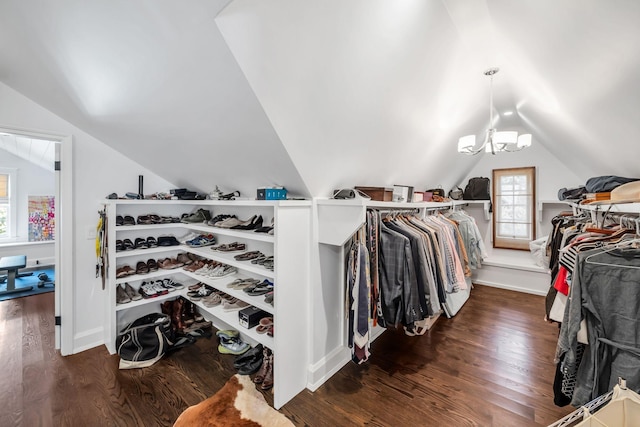 walk in closet with lofted ceiling, dark wood-type flooring, and a notable chandelier