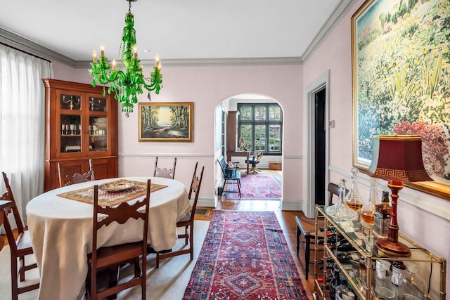 dining area featuring crown molding, hardwood / wood-style floors, and an inviting chandelier