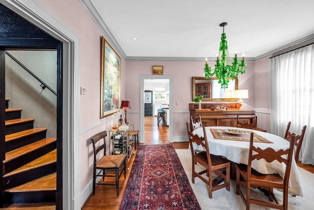 dining space with hardwood / wood-style floors, ornamental molding, and a chandelier