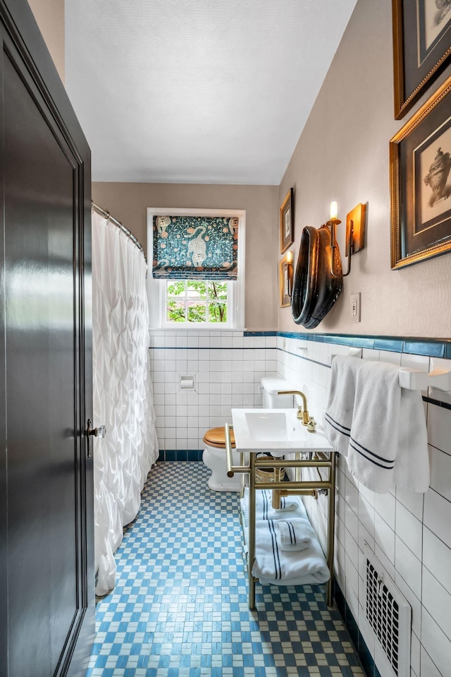 bathroom featuring toilet, radiator, sink, and tile walls