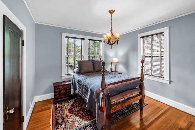 bedroom featuring wood-type flooring, ornamental molding, and a chandelier