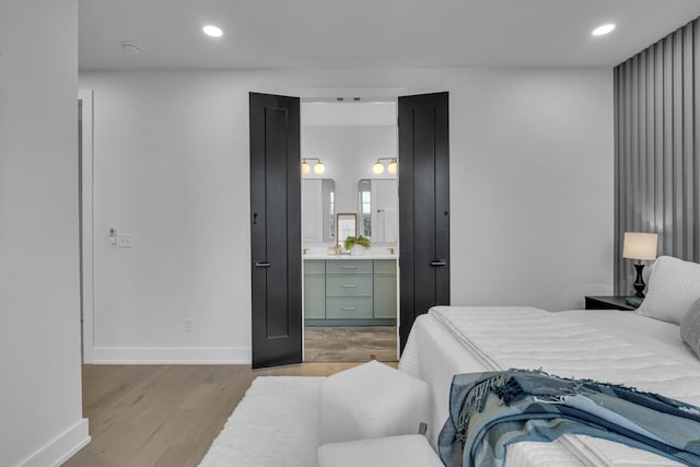 bedroom featuring connected bathroom and light wood-type flooring