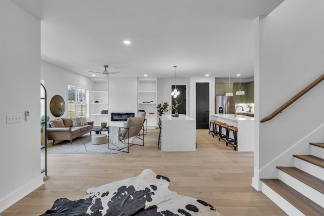 living room with sink, ceiling fan, and light hardwood / wood-style flooring