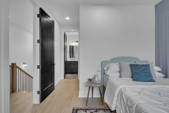 bedroom featuring ensuite bath and light hardwood / wood-style flooring