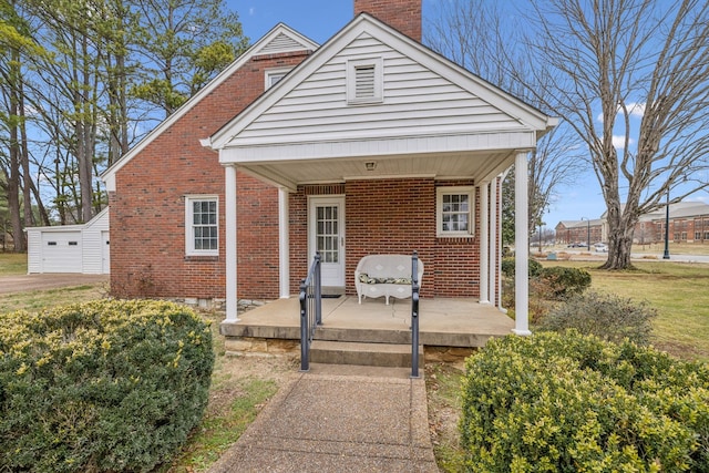 view of front facade featuring a garage, an outbuilding, and covered porch