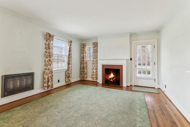 unfurnished living room with wood-type flooring, a brick fireplace, plenty of natural light, and heating unit