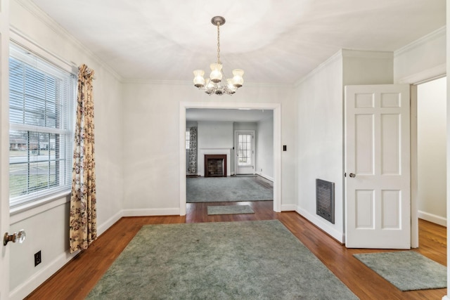 interior space with ornamental molding, a wealth of natural light, a notable chandelier, and dark hardwood / wood-style flooring