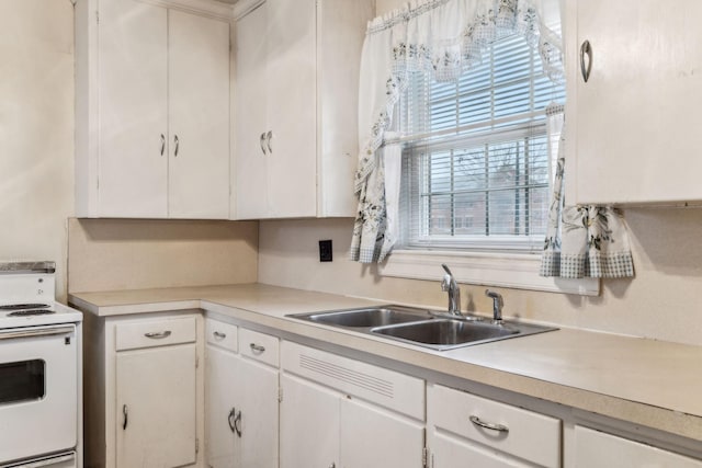 kitchen featuring white cabinetry, sink, and electric range