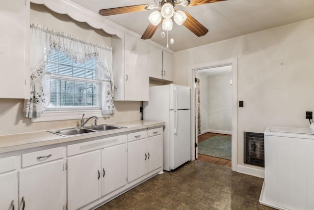 kitchen with washer / dryer, sink, heating unit, white cabinetry, and white fridge