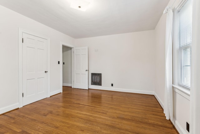 spare room with heating unit and hardwood / wood-style flooring