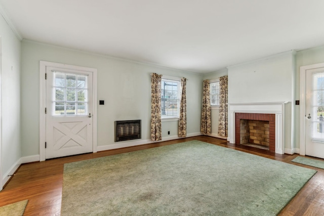 unfurnished living room featuring hardwood / wood-style flooring, a fireplace, heating unit, and crown molding