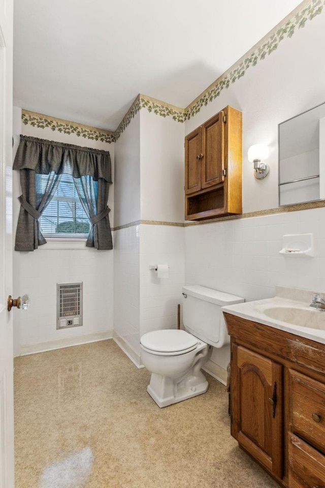 bathroom with tile walls, vanity, heating unit, and toilet