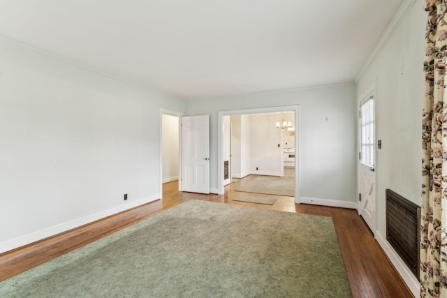 unfurnished room with ornamental molding, dark hardwood / wood-style floors, heating unit, and a notable chandelier