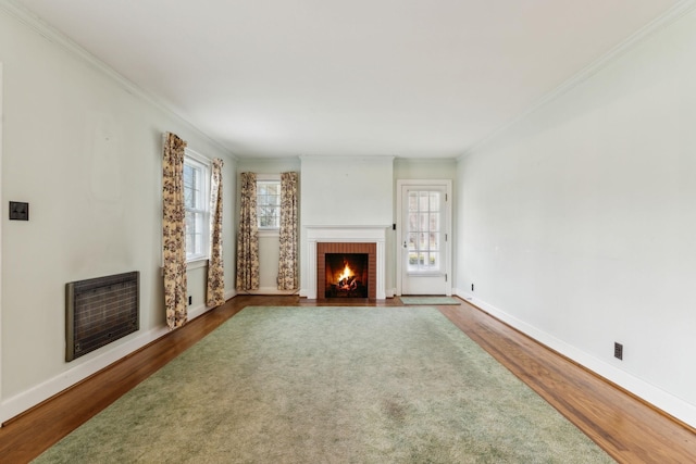 unfurnished living room featuring hardwood / wood-style flooring, ornamental molding, a brick fireplace, and heating unit