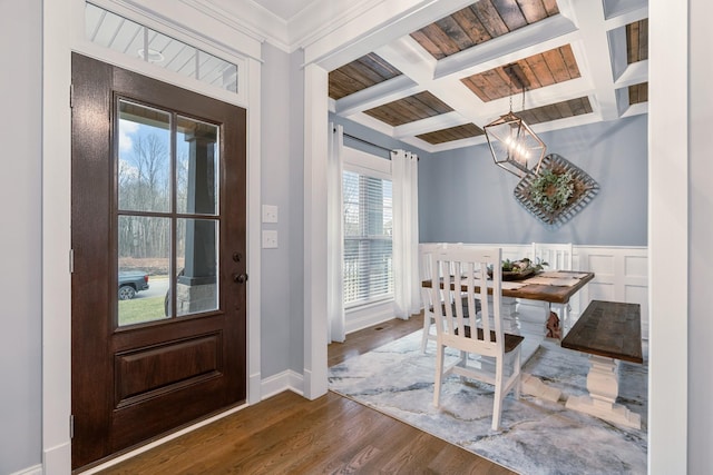 entrance foyer with an inviting chandelier, coffered ceiling, crown molding, dark wood-type flooring, and beam ceiling