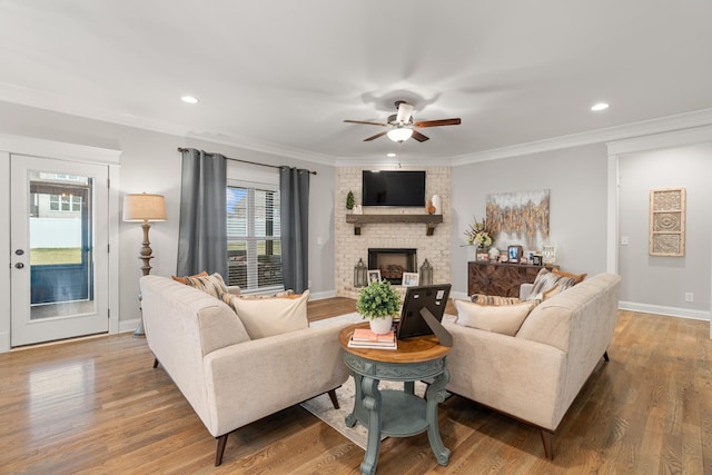 living room featuring wood-type flooring, a large fireplace, and ornamental molding