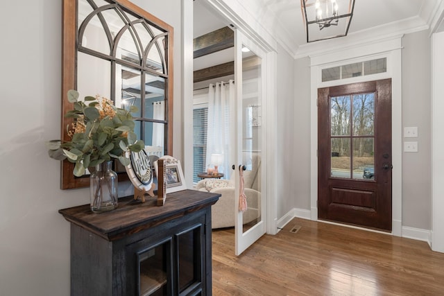 entryway featuring hardwood / wood-style floors, crown molding, french doors, and a chandelier