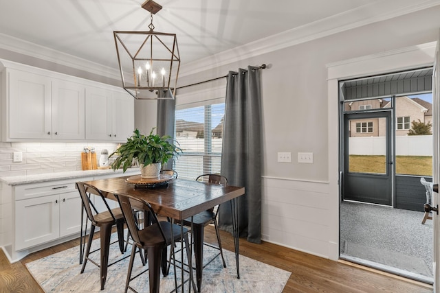 dining space featuring an inviting chandelier, crown molding, and dark wood-type flooring