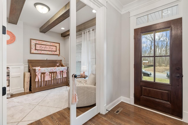 entryway with ornamental molding, beam ceiling, and light hardwood / wood-style floors