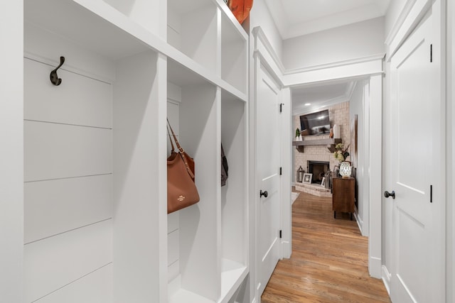 mudroom featuring crown molding, a fireplace, and light hardwood / wood-style floors