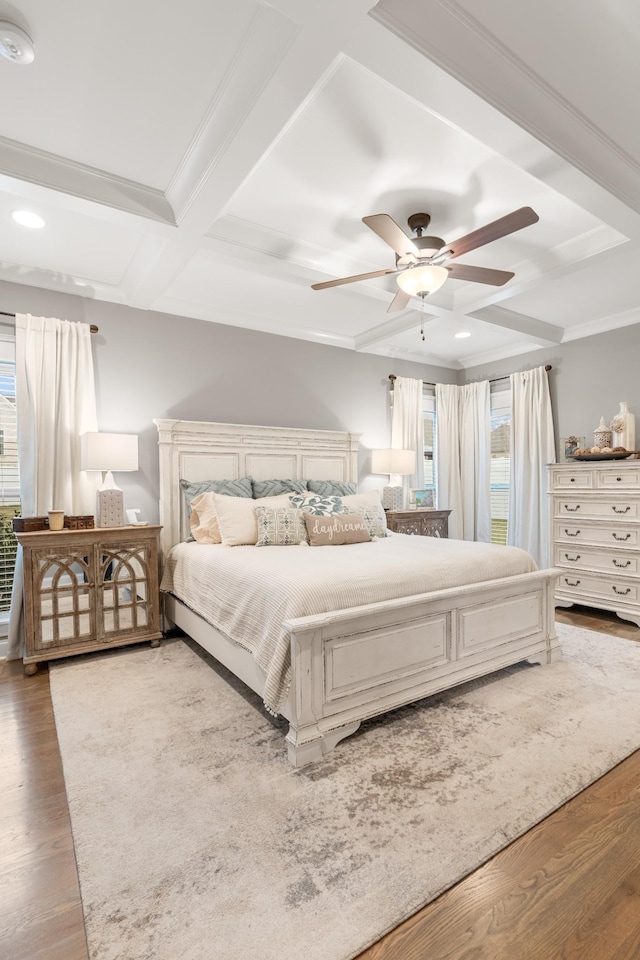 bedroom with wood-type flooring, coffered ceiling, ceiling fan, and crown molding