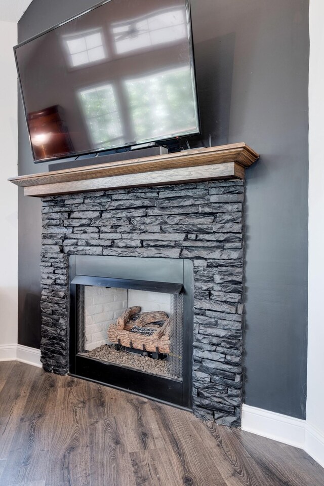 room details with hardwood / wood-style flooring and a stone fireplace