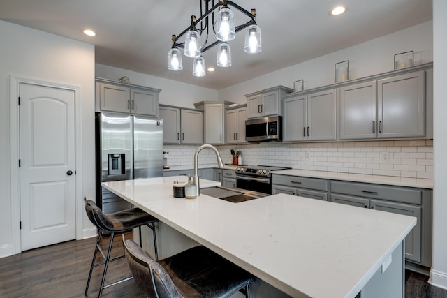 kitchen with hanging light fixtures, appliances with stainless steel finishes, a large island, and gray cabinetry