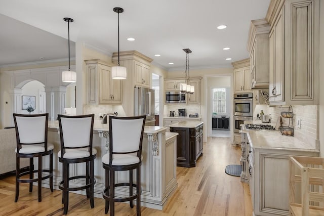 kitchen with stainless steel appliances, a kitchen island, light wood-style flooring, and pendant lighting