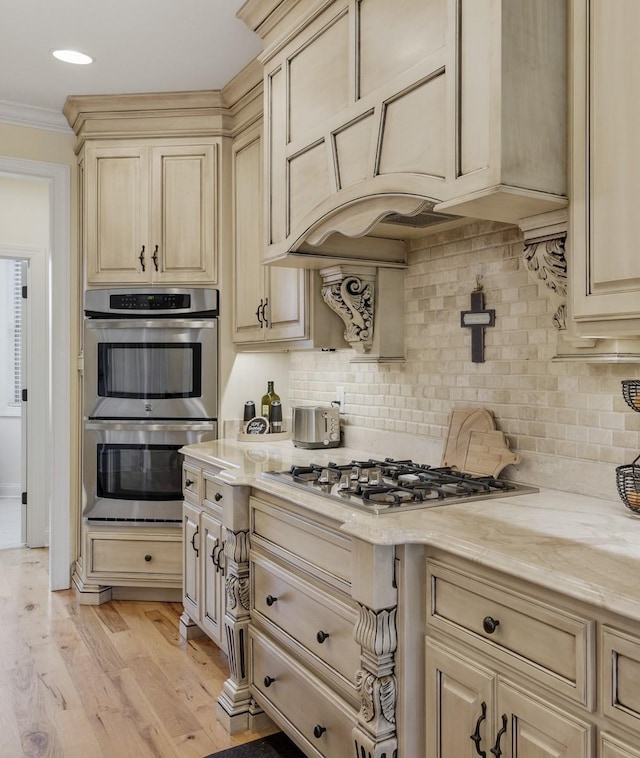 kitchen with tasteful backsplash, crown molding, light wood-type flooring, and appliances with stainless steel finishes