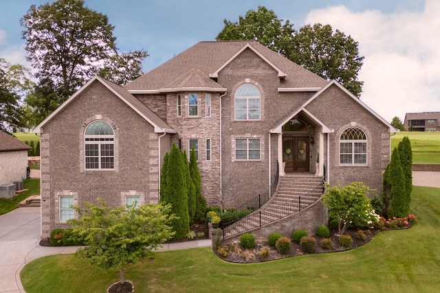 view of front facade featuring a front yard, brick siding, and stairs