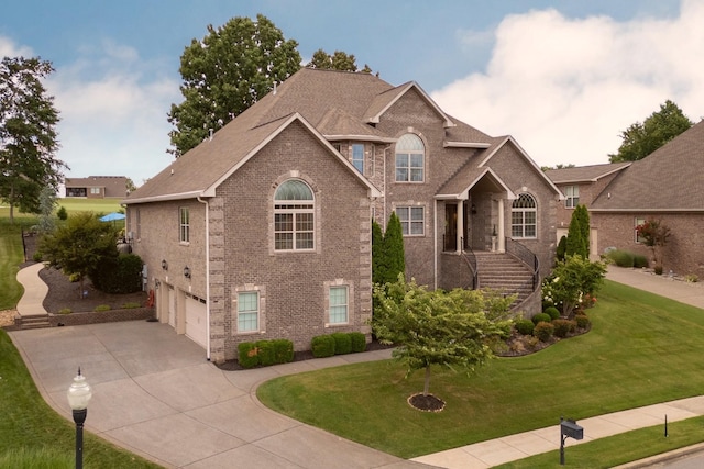 view of front facade with a front yard, brick siding, driveway, and an attached garage